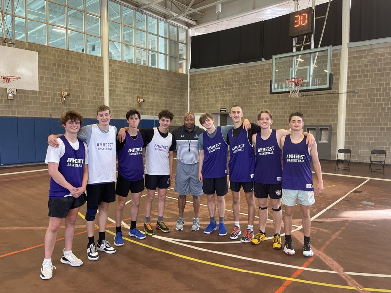 Tour athletes with a coach in Amherst College basketball reversibles.